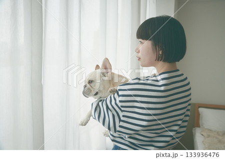 窓辺で犬を抱き抱える女性 133936476