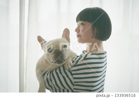 窓辺で犬を抱き抱える女性 133936518
