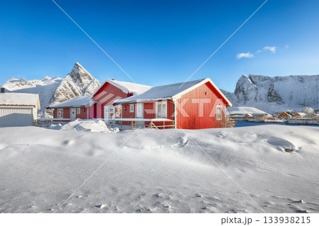 Traditional Norwegian  houses on the shore of  Reinefjorden on Toppoya island and snowy mountaines in background 133938215