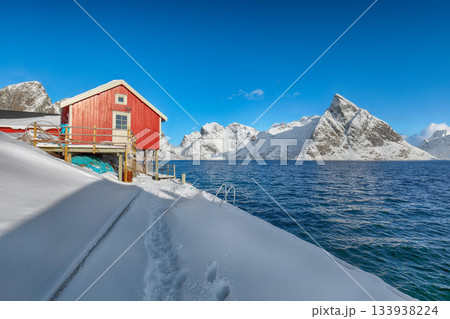 Traditional Norwegian houses on the shore of Reinefjorden on Toppoya island and snowy mountaines in background Traditional Norwegian houses on the shore of Reinefjorden on Toppoya island and snowy mountaines in background 133938224