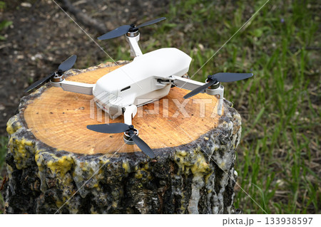 Small Quadcopter Drone copter parked on a birch tree stump rainy weather 133938597