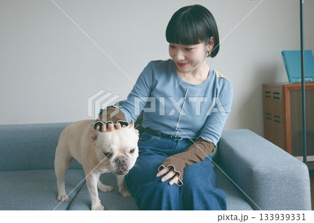 ソファでくつろぐ犬と若い女性 133939331