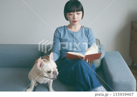 ソファで本を読む女性と犬 133939407