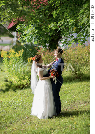 Bride and groom embracing under leafy tree canopy on wedding day Bride and groom embracing under leafy tree canopy on wedding day 133939432