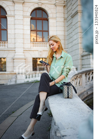 Woman sitting on street in Vienna using smartphone Woman sitting on street in Vienna using smartphone 133940824