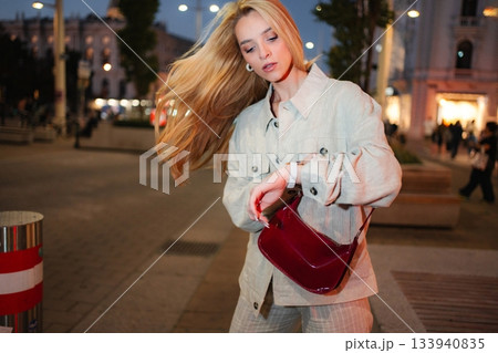 Young woman checking time on street in Vienna at night 133940835