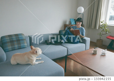 ソファでくつろぐ犬と若い女性 133942155