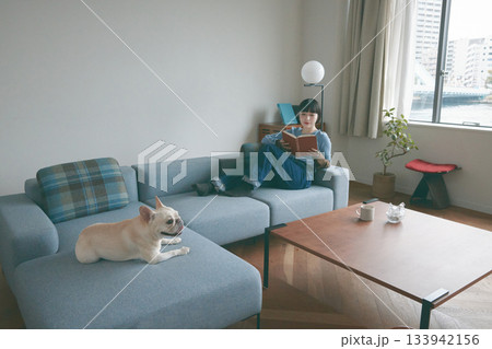 ソファでくつろぐ犬と若い女性 133942156