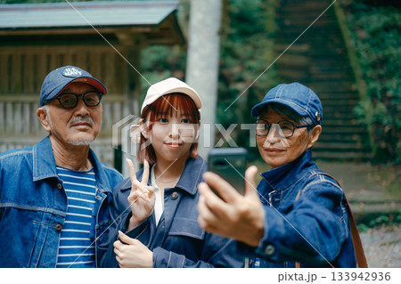 神社の鳥居前で親子3人がスマホで自撮りする家族旅行シーン 神社の鳥居前で親子3人がスマホで自撮りする家族旅行シーン 133942936