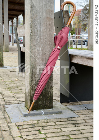 Outdoor. Closed umbrella hanging on a public bench 133943242