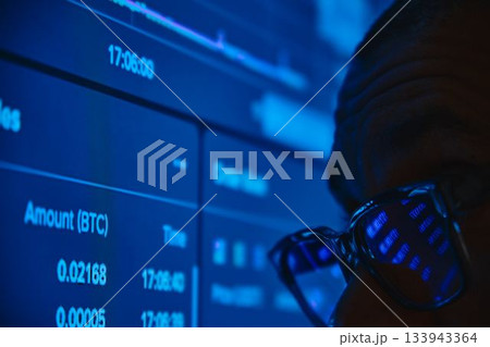 Man viewing cryptocurrency values on computer screen 133943364