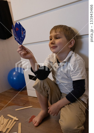 Little boy admiring a blue paper craft creation 133943466