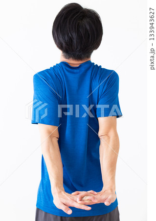 腕のストレッチ体操をするTシャツ姿のミドル男性 腕のストレッチ体操をするTシャツ姿のミドル男性 133943627