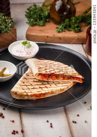 Grilled chicken quesadilla on black plate serving Grilled chicken quesadilla on black plate serving 133943841
