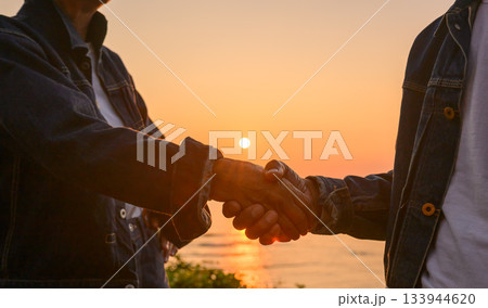 夕日と握手するシニア 133944620