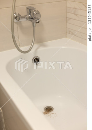 Water drain hole of a bathtub is clogged with long hair clump. Water drain hole of a bathtub is clogged with long hair clump. 133945188