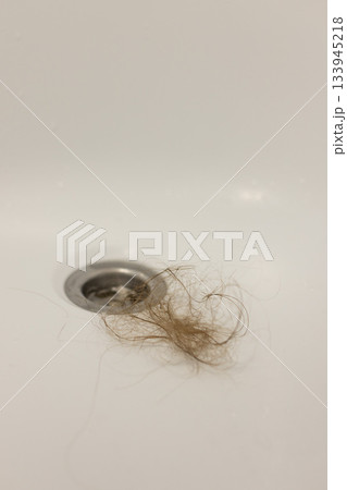 Water drain hole is clogged with long hair clump. Close-up. Water drain hole is clogged with long hair clump. Close-up. 133945218