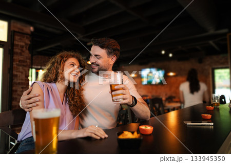 Couple enjoying drinks and snacks at a bar, looking at each other lovingly 133945350
