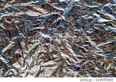 Crinkled aluminum foil texture with metallic shine and abstract pattern for background or design use Crinkled aluminum foil texture with metallic shine and abstract pattern for background or design use 133945660