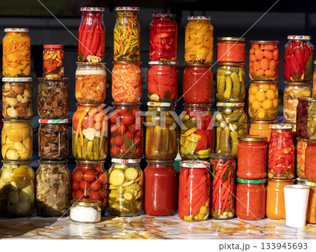 Colorful jars of pickled vegetables stacked on a market table for sale Colorful jars of pickled vegetables stacked on a market table for sale 133945693