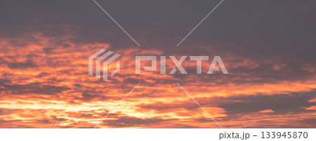 Vibrant sunset sky over the horizon with orange clouds and warm glow at dusk Vibrant sunset sky over the horizon with orange clouds and warm glow at dusk 133945870