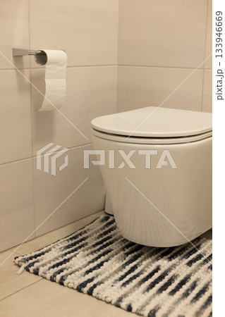 Interior of restroom with toilet bowl and carpet, tiled walls and floor. 133946669