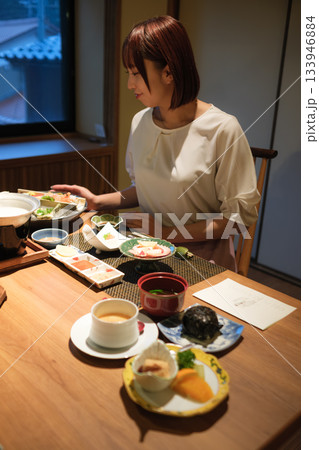 旅館の夕食時間｜くつろぐ女性と会席料理 133946884