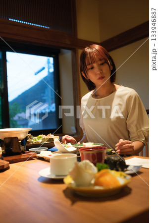 旅館の夕食時間｜くつろぐ女性と会席料理 133946887