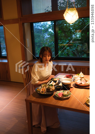 旅館の夕食時間｜くつろぐ女性と会席料理 133946898