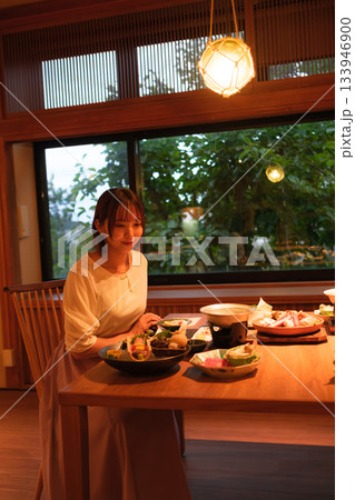 旅館の夕食時間｜くつろぐ女性と会席料理 133946900