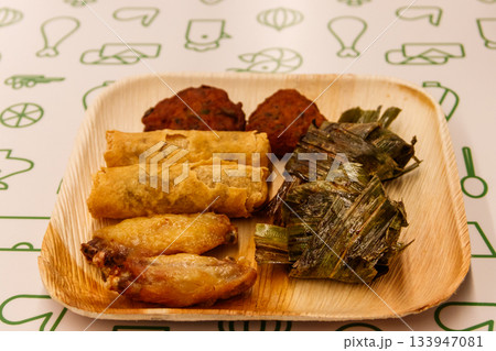 Set of thai food (fried chicken wrapped in pandan leaves, chicken wings, vegetable spring rolls, thai shrimp cake) on a table Set of thai food (fried chicken wrapped in pandan leaves, chicken wings, vegetable spring rolls, thai shrimp cake) on a table 133947081