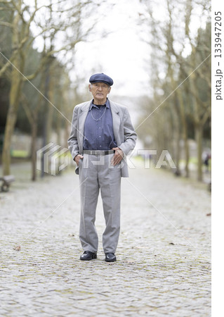 Senior man posing in a cobblestone path with trees 133947205