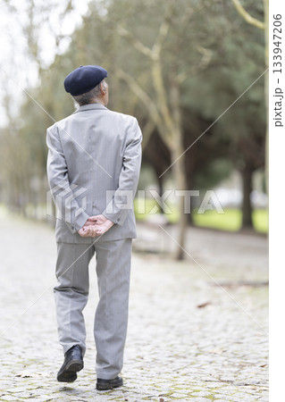 Elderly man enjoying a relaxing walk in the park 133947206