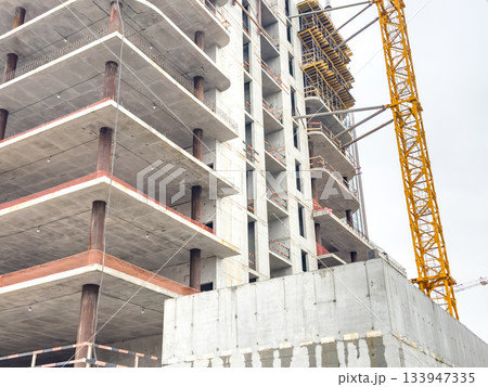 Urban building site, Industrial urban high rise under construction with machinery and exposed framework Urban building site, Industrial urban high rise under construction with machinery and exposed framework 133947335