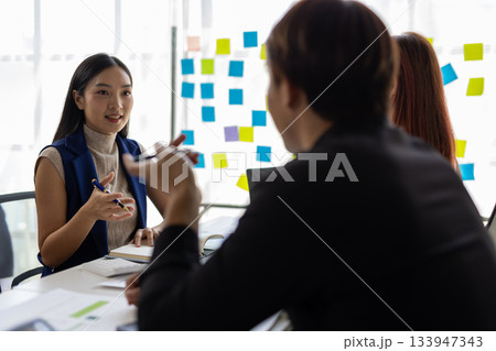 Asian businesswoman leading meeting discussing charts with coworkers in office. Asian businesswoman leading meeting discussing charts with coworkers in office. 133947343