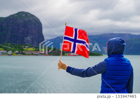 Tourist with norwegian flag on fjord 133947465