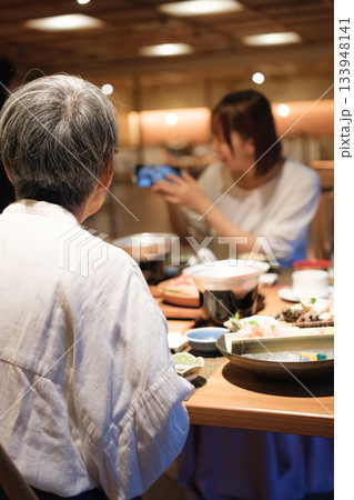 和食レストランで親子が食事を楽しみながら写真を撮るシーン 和食レストランで親子が食事を楽しみながら写真を撮るシーン 133948141