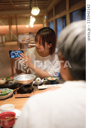 和食レストランで親子が食事を楽しみながら写真を撮るシーン 133948142