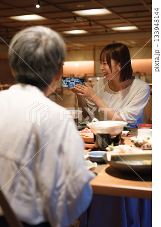 和食レストランで親子が食事を楽しみながら写真を撮るシーン 133948144