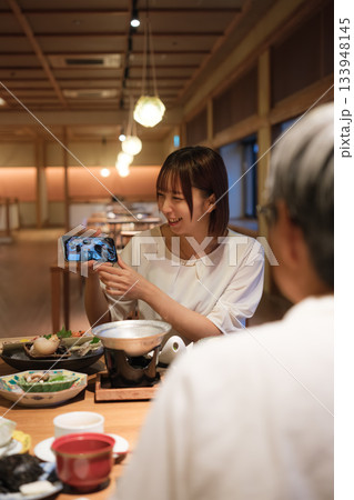 和食レストランで親子が食事を楽しみながら写真を撮るシーン 133948145