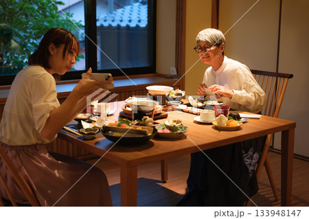 和食レストランで親子が食事を楽しみながら写真を撮るシーン 和食レストランで親子が食事を楽しみながら写真を撮るシーン 133948147