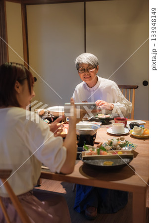 和食レストランで親子が食事を楽しみながら写真を撮るシーン 和食レストランで親子が食事を楽しみながら写真を撮るシーン 133948149