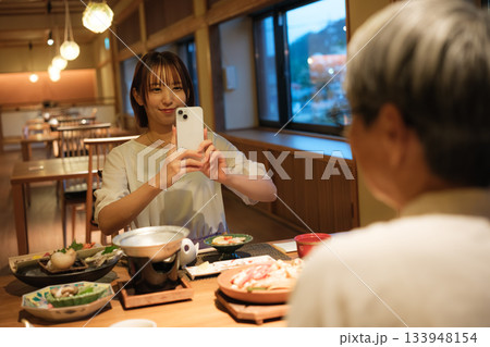 和食レストランで親子が食事を楽しみながら写真を撮るシーン 和食レストランで親子が食事を楽しみながら写真を撮るシーン 133948154
