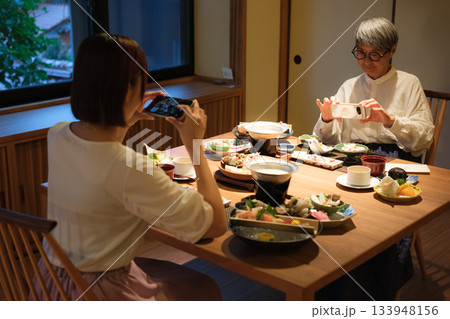 和食レストランで親子が食事を楽しみながら写真を撮るシーン 和食レストランで親子が食事を楽しみながら写真を撮るシーン 133948156