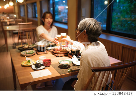 旅館の夕食で親子が乾杯を交わす温かい団らんのひととき 旅館の夕食で親子が乾杯を交わす温かい団らんのひととき 133948417