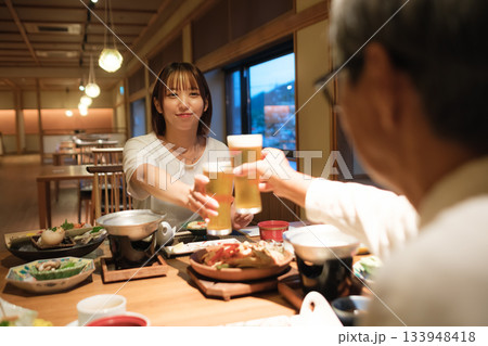 旅館の夕食で親子が乾杯を交わす温かい団らんのひととき 旅館の夕食で親子が乾杯を交わす温かい団らんのひととき 133948418