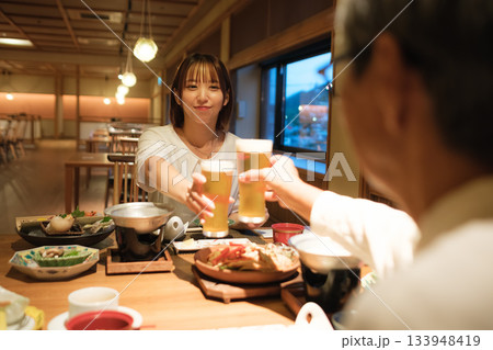 旅館の夕食で親子が乾杯を交わす温かい団らんのひととき 旅館の夕食で親子が乾杯を交わす温かい団らんのひととき 133948419