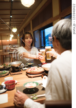 旅館の夕食で親子が乾杯を交わす温かい団らんのひととき 133948422