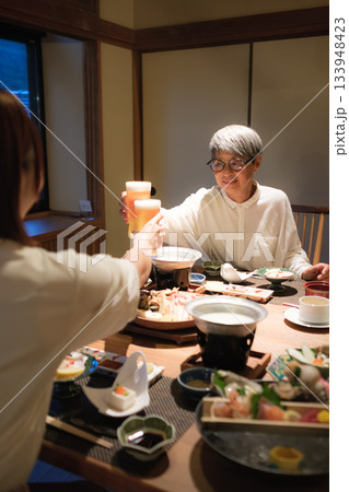 旅館の夕食で親子が乾杯を交わす温かい団らんのひととき 旅館の夕食で親子が乾杯を交わす温かい団らんのひととき 133948423