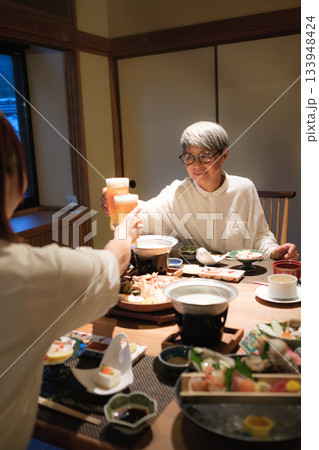 旅館の夕食で親子が乾杯を交わす温かい団らんのひととき 133948424